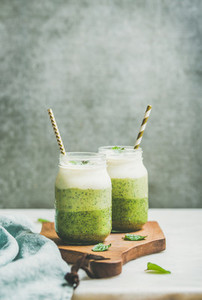 Ombre layered green smoothies with mint in jars with straws