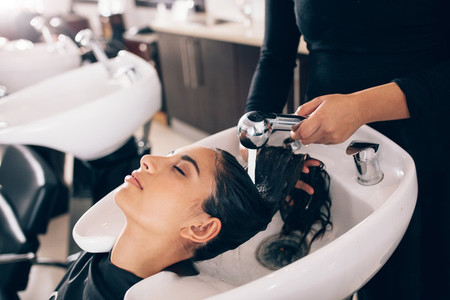 Hairdresser washing hair of customer at salon