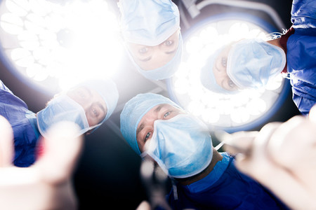 Team of surgeons operating under surgery lights