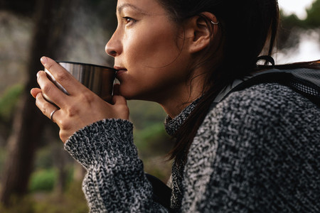 Young asian female hiker drinking coffee