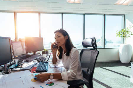 Businesswoman speaking over phone in office