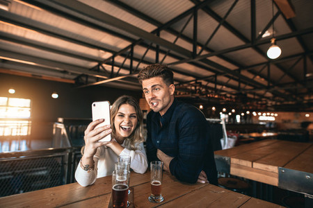 Couple taking selfie on mobile phone inside the bar