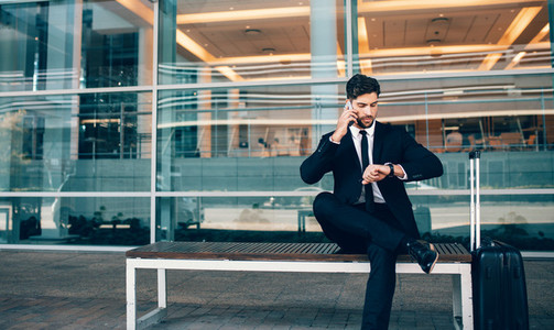 Business traveler talking on phone and checking time