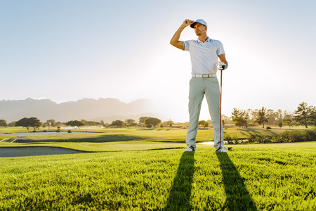 Professional male golfer standing on golf course