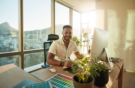 Smiling male designer sitting at his desk