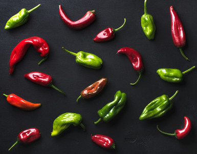 Pattern of small colorful hot chili peppers on black background