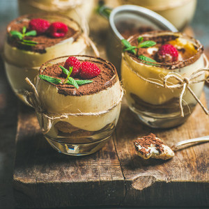 Homemade dessert Tiramisu in glasses with fresh raspberries on board