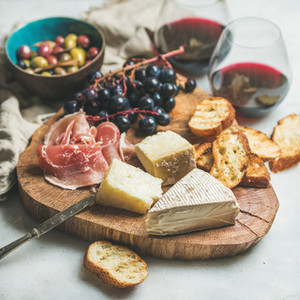 Red wine and snack variety on wooden board