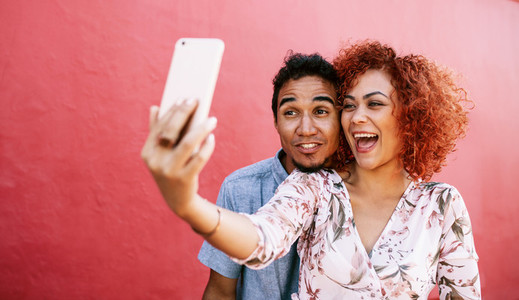 Young couple posing for a selfie using mobile phone