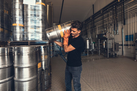 Brewer with keg at brewery factory warehouse