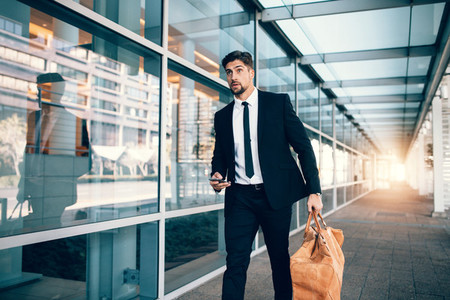 Businessman carrying bag and smart phone at airport