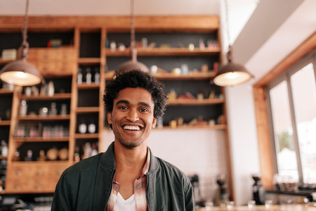 Handsome young african guy standing in a coffee shop and smiling