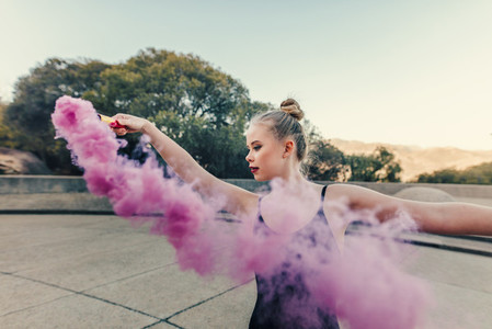 Female ballet dancer practicing dance moves using a smoke bomb