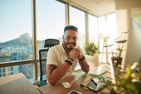Male designer sitting at his desk and smiling