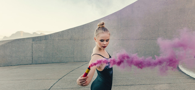 Female ballet dancer practicing dance moves using a smoke bomb