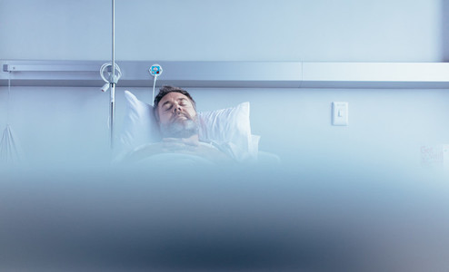 Mature sick male patient sleeping in hospital bed