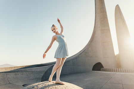 Female ballet dancer practicing dance moves on a rock