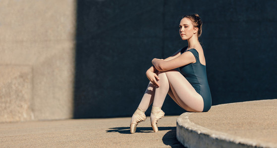 Female ballet dancer sitting gracefully while resting her toes o