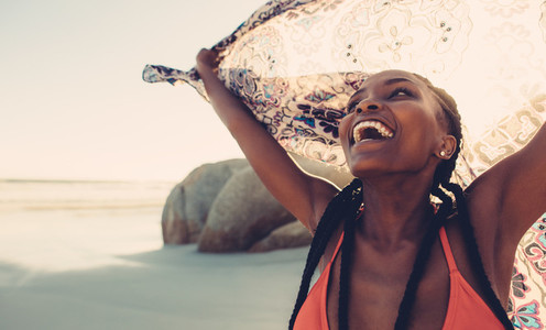 Laughing woman with scarf on beach