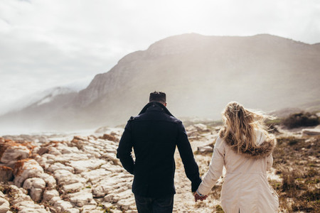 Couple walking through rocky coastline on a winter day