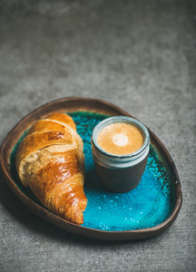 Cup of espresso and croissant in blue tray  grey background