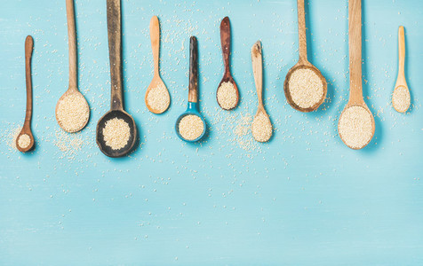 Quinoa seeds in different spoons over blue background  copy space