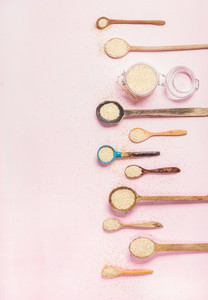 Quinoa seeds in different spoons and jar over pink background