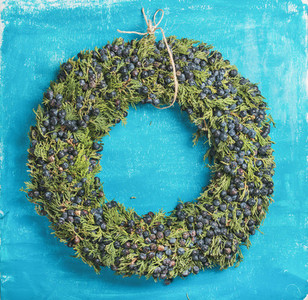 Christmas decorative wreath over bright blue painted wall background