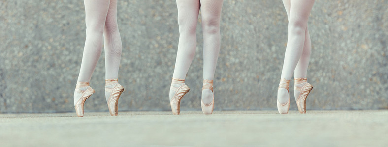 Closeup of legs of three ballet dancers in pointes