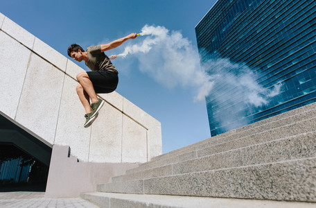 Man doing parkour jump with smoke grenade