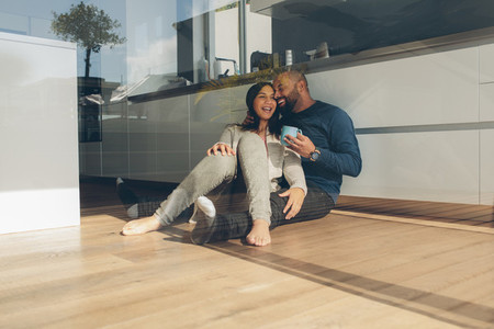 Romantic young couple sitting on kitchen floor in morning