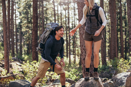 Hiking couple walking on rocks in forest wearing backpacks