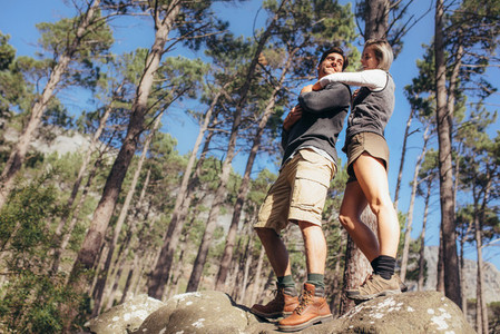 Woman holding her male partner from behind standing on rocks