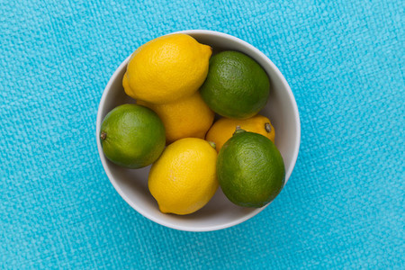 Lemon and lime in bowl on blue background