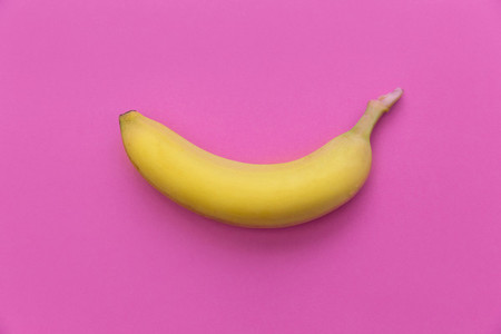 Yellow banana on bright pink background