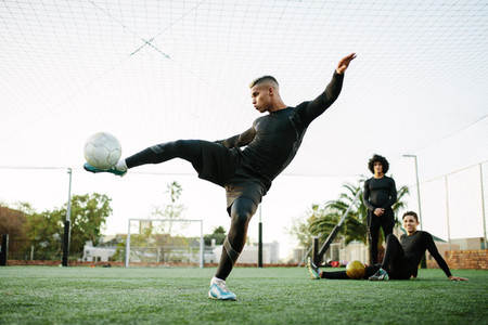 Player kicking soccer ball on field