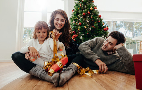 Small family having fun opening Christmas gifts
