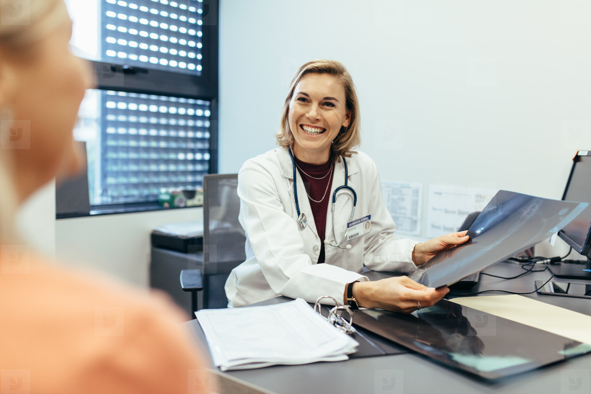 Smiling doctor holding x ray communicating with patient