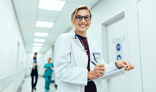 Female physician in hospital corridor writing prescription