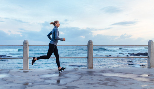 Fitness woman running on a road by the sea