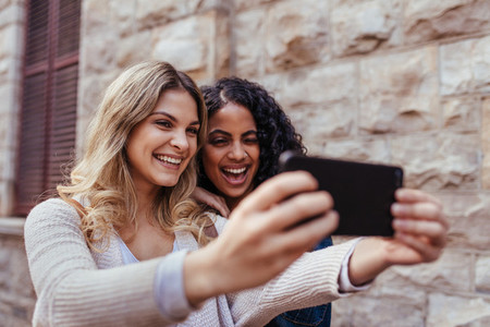 Two women clicking a selfie outdoors