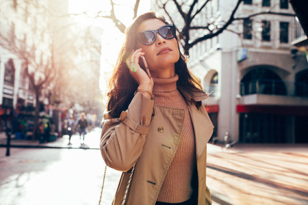 Fashionable female walking on street using phone