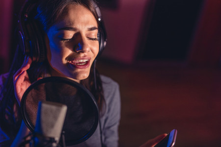 Female singer recording a song in studio