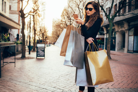 Woman using a smart phone while shopping in the city
