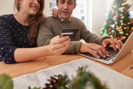 Couple shopping online for christmas with credit card and laptop