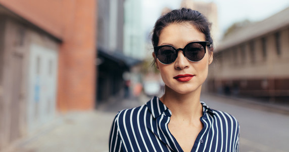 Woman with sunglasses walking outdoors on the city street