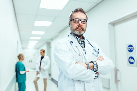 Experienced doctor standing in hospital corridor