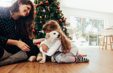 Happy mother and daughter celebrating Christmas with their dog