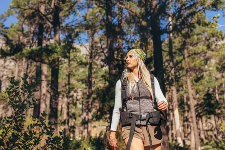 Woman walking in forest wearing a backpack