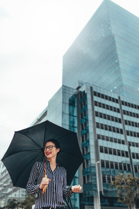 Happy business woman outdoors with umbrella